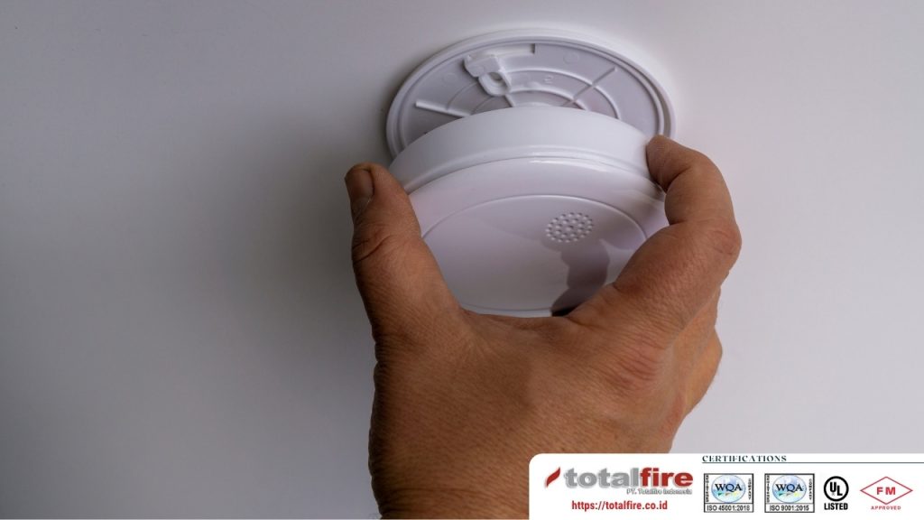 teknisi profesional memasang smoke detector sebagai bagian dari service dan perawatan fire alarm berkala